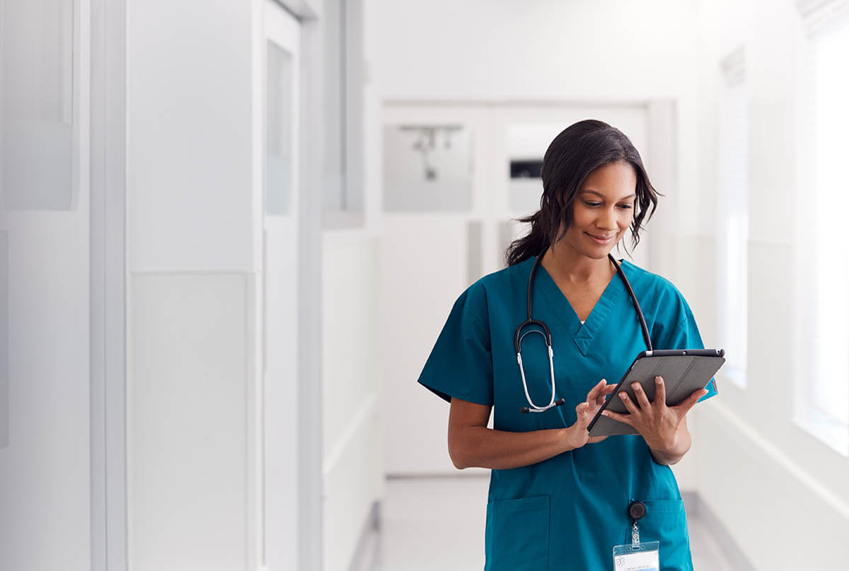 Female Doctor Wearing Scrubs In Hospital Corridor Using Digital Tablet How to Leverage PPM Software in the Healthcare Industry